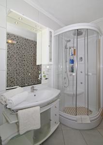 a white bathroom with a shower and a sink at Apartments Šiljug in Cavtat