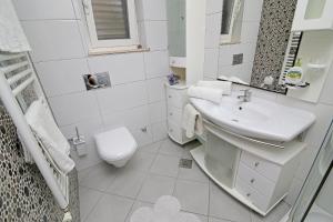 a white bathroom with a sink and a toilet at Apartments Šiljug in Cavtat