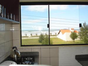 a kitchen with a view of the beach from a window at Pousada Cheiro De Mar in Imbituba