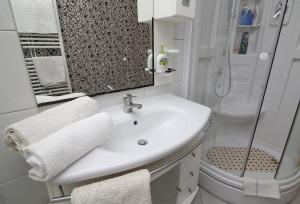 a white bathroom with a sink and a shower at Apartments Šiljug in Cavtat