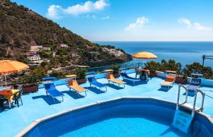 a swimming pool with chairs and umbrellas and the ocean at Le Terrazze sul mare in Ustica