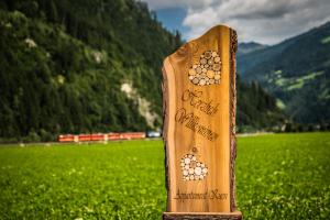 a wooden sign in front of a green field at Appartement Kuen in Zell am Ziller