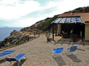 un grupo de sillas y una casa con el océano en Isola d'Elba Come in Barca, a un Tuffo dal Mare, en Capoliveri