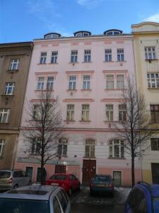 プラハにあるCity Castle Aparthotelの車が目の前に停まったピンクの建物