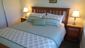 HagleyにあるLittle Sunnyside Accommodationのベッド1台(青と白の枕、ランプ2つ付)