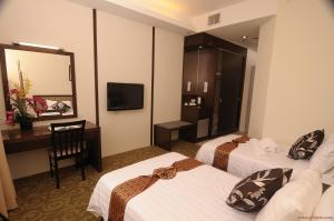 Habitación de hotel con 2 camas, escritorio y TV. en Seemsoon Hotel en Ipoh