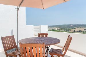 a wooden table with chairs and an umbrella on a balcony at Aljezur Old Town in Aljezur