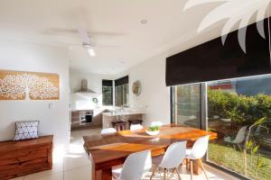 a kitchen and dining room with a wooden table and white chairs at Boom 8 Boomerang Beach in Blueys Beach