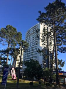 a tall white building with trees in front of it at Green Life - Club Vacacional y SPA in Punta del Este