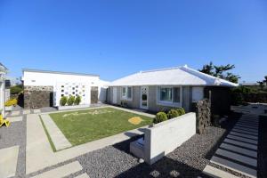 a house with a lawn in front of it at Bookmark Guesthouse in Seogwipo