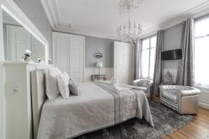 una camera da letto bianca con un letto e una sedia di La Demeure De Charme a Troyes