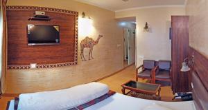 a hotel room with a tv and a bed and chairs at Hotel Rangoli in Jaipur