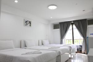 3 weiße Betten in einem Zimmer mit Fenster in der Unterkunft Thanyachatra Boutique in Phetchaburi