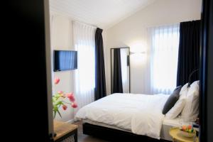 1 dormitorio con 1 cama con sábanas blancas y ventanas en City Port Hotel, en Haifa