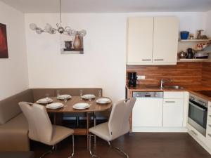 uma cozinha com mesa e cadeiras e uma cozinha com armários brancos em Kitz Residenz Appartement 10 Kaprun em Kaprun