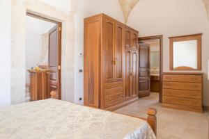 - une chambre avec un lit et des placards en bois ainsi qu'une salle de bains dans l'établissement Masseria Cappella, à Martina Franca