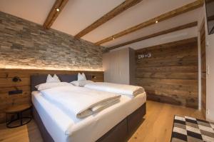 a bedroom with two beds and a brick wall at Appartment Hossler in Valdaora