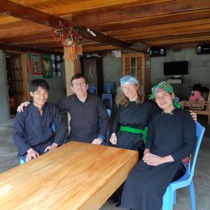 un grupo de personas sentadas alrededor de una mesa de madera en Organic Farm Homestay en Sa Pa