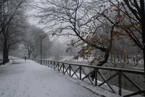 トリノにあるAppartamento Borgo Auroraの雪に覆われた歩道を柵の横を歩く者