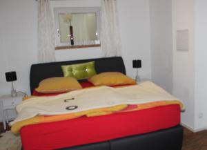 フリンツバッハにあるFerienwohnung Hilpertのベッドルーム1室(大型ベッド1台、赤と黄色の毛布付)
