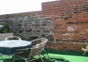 uma mesa e cadeiras ao lado de uma parede de tijolos em Ferienwohnung Im Wachturm em Tangermünde