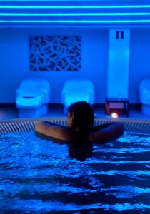 a woman is laying in a swimming pool at Hotel & Spa Real Ciudad De Zaragoza in Zaragoza