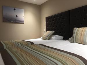 a bedroom with two beds and a large headboard at Camelia Hotel in Southend-on-Sea