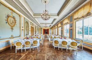a banquet hall with tables and chairs and windows at Hotel Chateau Béla in Belá