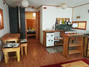 a kitchen with a refrigerator and wooden tables and chairs at Eco-Cabañas Quetroleufu in Pucón