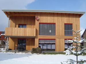 a wooden building with red windows in the snow at Ferienhaus Brütting in Pottenstein