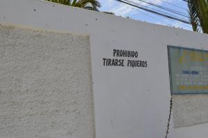 una señal en el costado de una pared blanca en Cabañas Hecmar, en Pichilemu