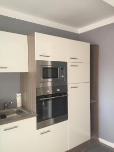a kitchen with white cabinets and a microwave at Hollandia City House in Hasselt