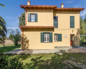 奧里斯塔諾的住宿－Fra il Verde e l'Azzurro，一座黄色的房子,有绿色百叶窗和庭院