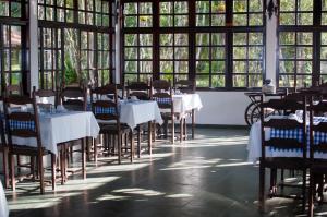 a dining room with tables and chairs and windows at Chácara Pimentão Vermelho in Peruíbe