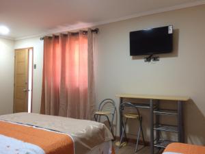 a room with two beds and a flat screen tv on the wall at Hostal Luna del Mar in La Serena