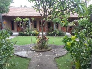 a garden in front of a house with a tree at Molleh Guest House in Pemuteran