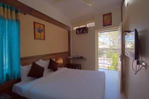 a bedroom with a white bed and a sliding glass door at Gems 9 Airport Hotel in Nedumbassery