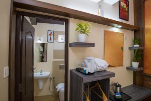 a bathroom with a sink and a toilet and a mirror at Gems 9 Airport Hotel in Nedumbassery