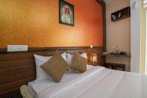 a bedroom with a white bed with an orange wall at Gems 9 Airport Hotel in Nedumbassery