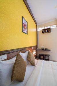 a bedroom with a large bed with a yellow wall at Gems 9 Airport Hotel in Nedumbassery