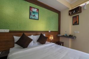 a bedroom with a white bed with a green wall at Gems 9 Airport Hotel in Nedumbassery