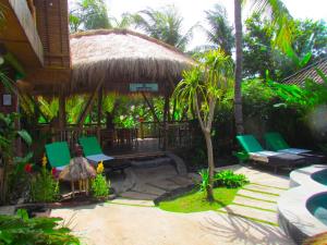 une terrasse avec des chaises vertes et une cabane de chaume dans l'établissement L'Bulu Menjangan, à Banyuwedang