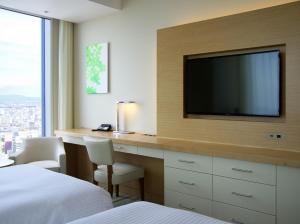 a hotel room with a desk with a tv and a bed at Nagoya JR Gate Tower Hotel in Nagoya