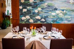 a table with wine glasses and a painting at MH Hotel Piacenza Fiera in Piacenza