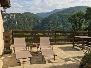 2 sillas y una mesa en un patio con montañas en Gite de Serrelongue en Montségur