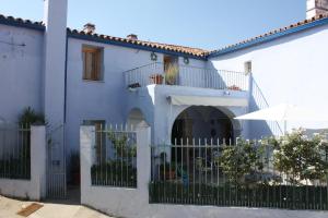 een wit huis met een poort en een paraplu bij La Cantarera in Herguijuela