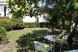 two chairs and a table under a tree at L'Ecrin du Serein in Sainte-Vertu