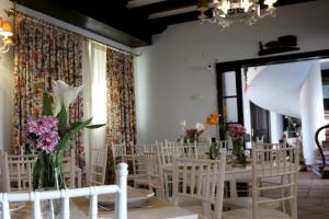 um quarto com cadeiras brancas, mesas e flores em Palacio Doñana , Rural & Luxury em El Rocío