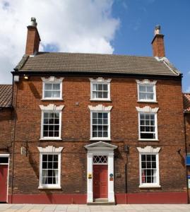 a red brick building with white windows and a red door at Bail Mews in Lincoln