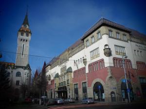 a tall building with a clock tower on a street at VINYL House. A quiet street in the centre of city in Târgu-Mureş